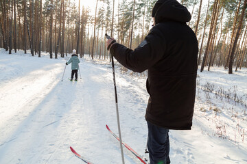Dad and daughter skiing in the winter forest