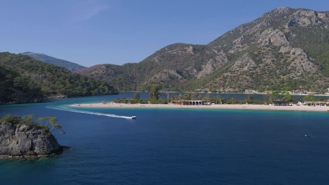 Pull-back aerial view of the boats sailing off Oludeniz shore and Bozyigit Burnu in Fethiye, Turkey