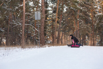 Father and daughter having fun with snow tube in the forest
