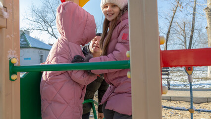 Grandfather with grandchildren playing on the playground on a cold winter day