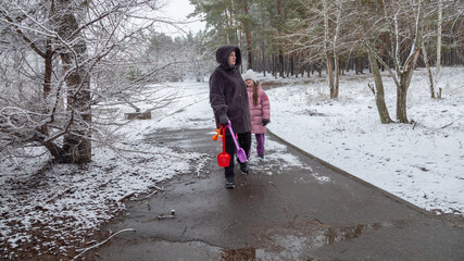 Grandmother and girls walk along a snowy street in winter