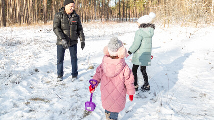 Little girls with her grandfather having fun on snowy winter day