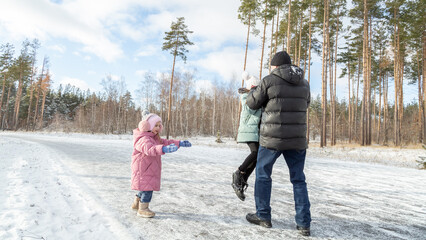 Little girls with her grandfather walking in park on snowy winter day