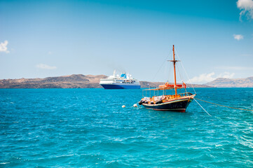 Obraz premium Santorini island, Greece. Cruise ship and wooden boat near the coast.