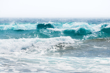 Waves on the beach in windy day. Santorini island, Greece. Blue sea and the blue sky.