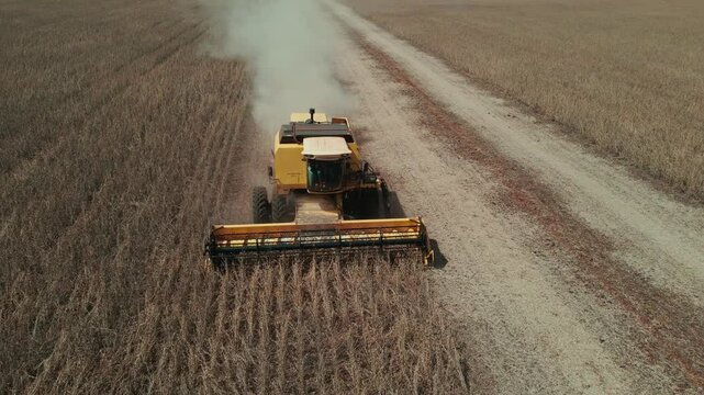 Frontal aerial shot of soybean harvest, with the harvester raising dust while threshing soybeans.