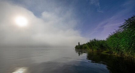A foggy lake with a full moon reflecting on the water