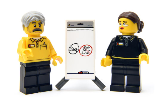 Lego minifigures of employee or college with presentation of new American fees. Editorial illustrative image of popular plastic toy constructor.