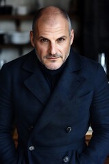 Obraz premium An accomplished leader, stationed in front of a sleek wooden desk, holds a calm, focused expression that commands respect. The vibrant contrast highlights the suit’s fitted lines, wiping away 