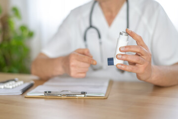 Fototapeta premium Doctor is showing an asthma inhaler during a medical consultation, providing guidance on its correct usage for effective treatment and relief