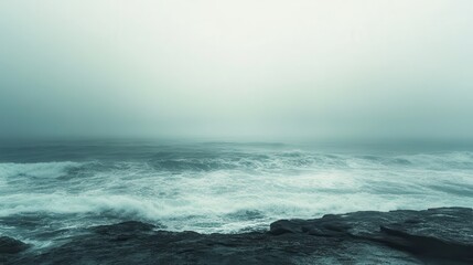 Coastal storm waves crashing on rocks in fog