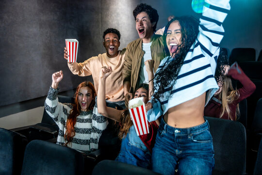 Young people cheering and watching a movie at the cinema