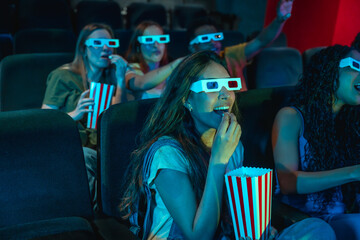 Friends watching 3d movie and eating popcorn in cinema