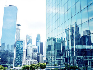 Obraz premium Urban skyline with modern glass skyscrapers mirrored on a building facade, realistic style, bright daylight background, concept of city architecture. Ai generative