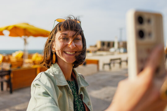 Girl on vacation takes photos of city and beach on phone for social networks. travel and content creation. - Powered by Adobe