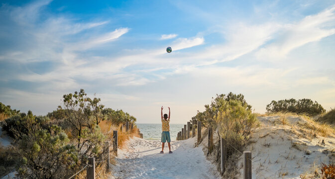 Boy playing with his ball on a beautiful day at the beach