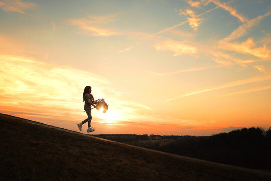 Profile tween girl riding stick horse against beautiful sunset s