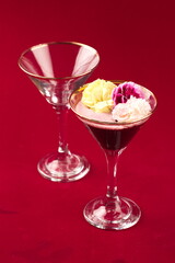 Cocktail glasses with fruit garnish with empty glass glasses on red background