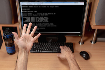 Frustrated angry man working with computer and looking error warning window operating system. Man observing hanging operating system on monitor, viewed from behind