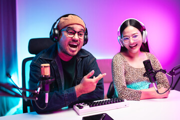 Teenagers, men and women, host podcasts in a room using LED lights, computers, headphones, condenser microphones, and tablets to share their knowledge and experiences through live online broadcasts.