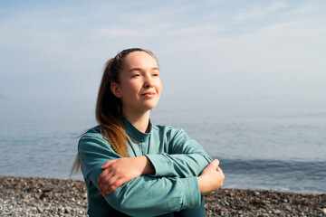 Peaceful young woman sitting on the seashore, enjoying the moment, basking in the morning sun,...