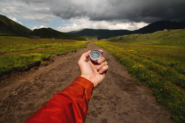 Man explorer searches for direction with a compass in a green field on an off-road. A first-person...