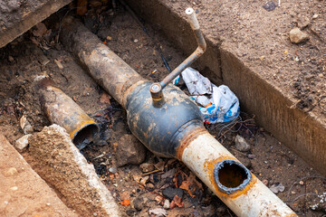 A pipe that has a hole in it is currently laying in the dirt