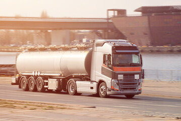 Modern Silver Road Tanker Truck Driving Near Urban Waterfront