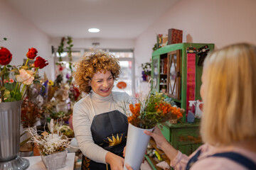 Cheerful florist shares vibrant flowers with a happy customer in a cozy shop