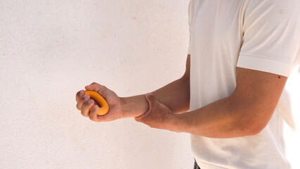 Young man holding yellow expander in hand on white shade wall background