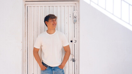 Young handsome man portrait, white metal door on background
