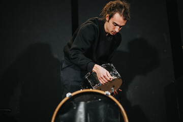 A musician setting up a drum on stage before a performance, showcasing concentration and...