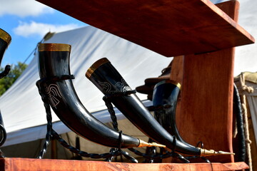 A close up on a set of massive horns and cups decorated with golden elements and having some carvings on them, displayed during a viking and medieval themed festival organized in Poland in summer