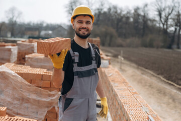 Showing the brick. Construction worker is at job with outdoors
