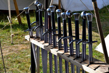 A set of metal and iron swords with their handles made out of leather seen next to cloth tents...