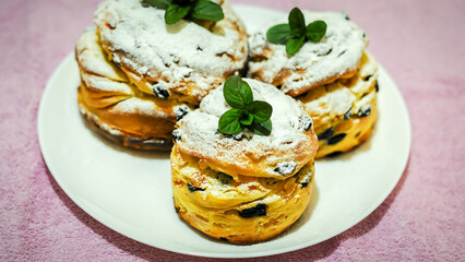 Three delicious cruffins dusted with powdered sugar and garnished with fresh mint sit on a plate.