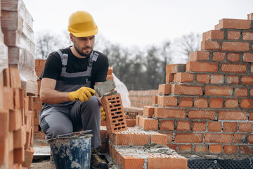 Applying concrete. Construction worker is at job with bricks outdoors