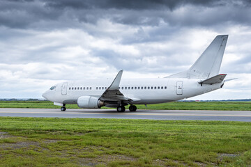 White passenger plane taxiing at the airport in cloudy weather