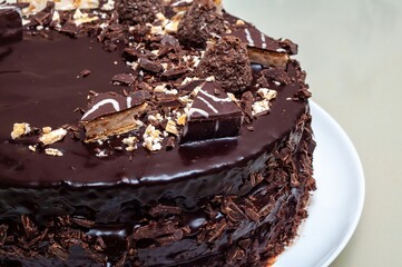 A close-up shot of a beautifully decorated chocolate cake on a white plate, invitingly tasty.