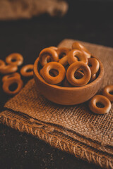Crispy round bagels in a wooden bowl on rustic burlap fabric. Traditional Eastern European snack...
