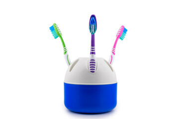 three colorful bright toothbrushes stand in a plastic toothbrush holder stand