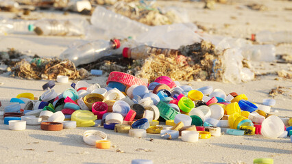 Colorful plastic bottle caps slow-motion on a polluted beach, plastic waste on coastal areas