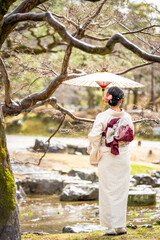 Woman in Kimono with Traditional Umbrella in Japanese Garden. Kyoto, Japan.