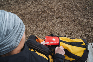 A dedicated person meticulously organizing a comprehensive First Aid Kit in a beautiful outdoor...