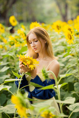 Cute european young model girl posing and having fun in a field full of blooming sun flowers. Showing freedom, innocence and youth