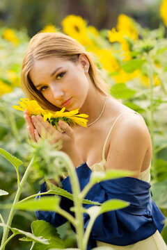 Cute european young model girl posing and having fun in a field full of blooming sun flowers. Showing freedom, innocence and youth