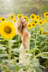 Cute european young model girl posing and having fun in a field full of blooming sun flowers. Showing freedom, innocence and youth