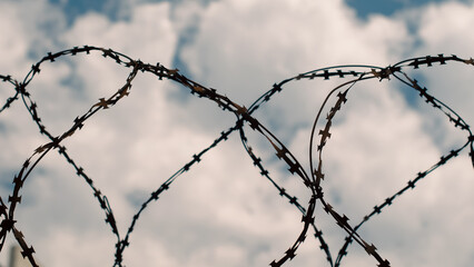 rusty barbed wire fenced against the blue sky and white clouds