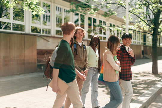 Diverse high school students walking and talking together on campus