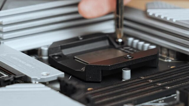 The master tightens the screws to attach the backplate to the motherboard. PC assembly. Installing a liquid cooling system for the processor. 4k